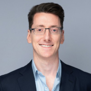 A person in a suit smiling

Description automatically generated